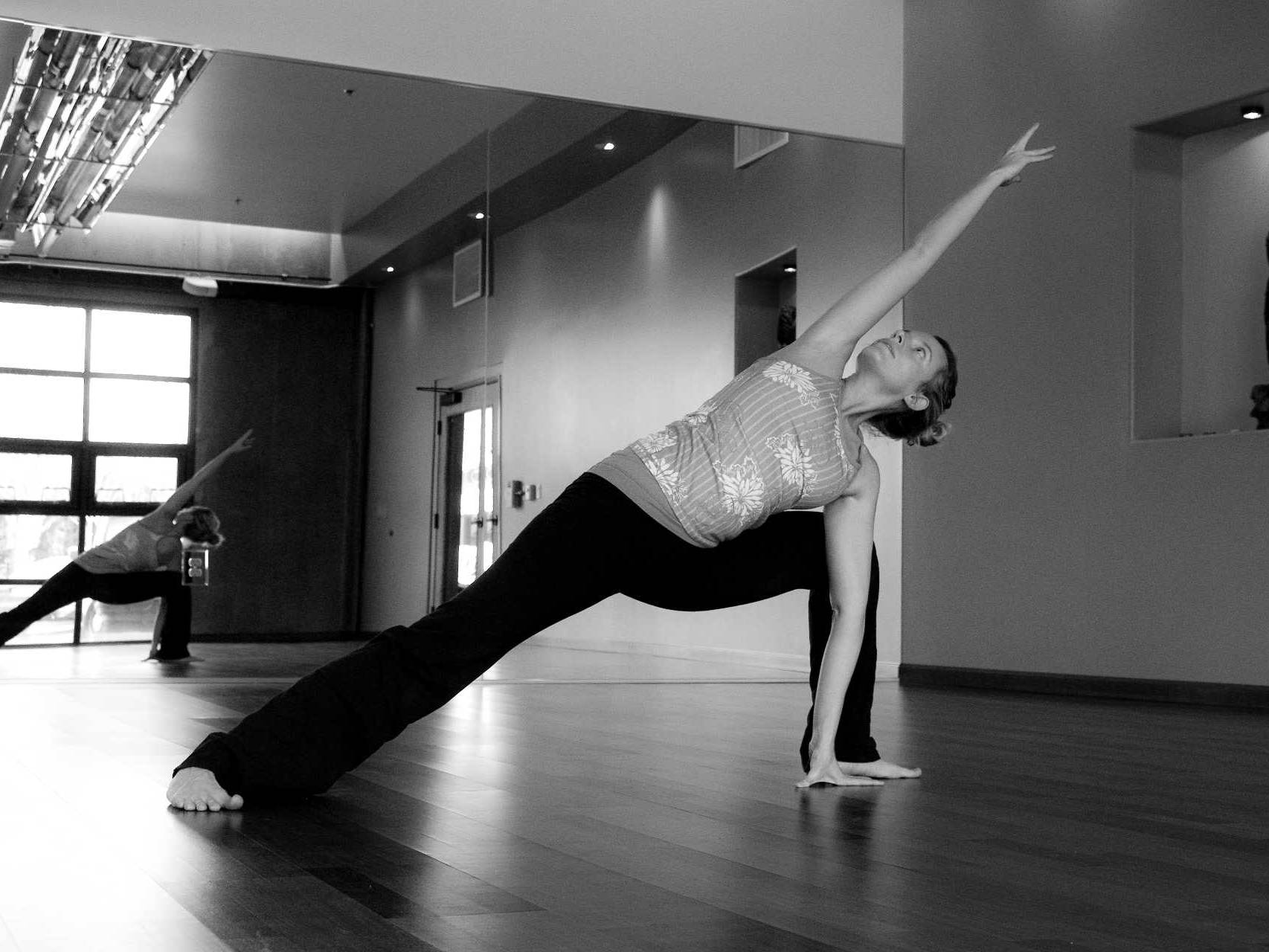 hot Yoga studio practice room with woman striking yoga posing