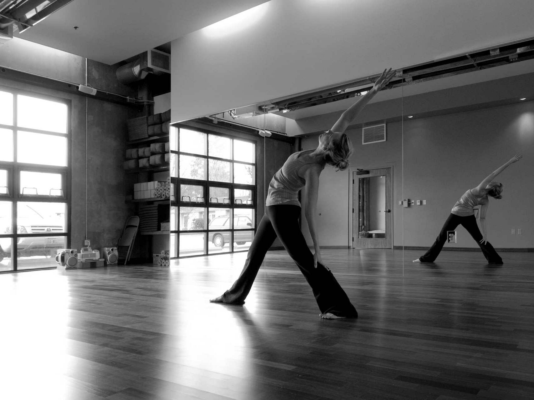 light and airy hot yoga studio practice room w woman striking yoga pose in mirror